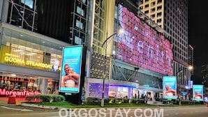 A hotel with a large digital display on the facade, a visible restaurant sign, and a clear view of the street. - Zenith Suites JBCC by OKGOSTAY (Johor Bahru)