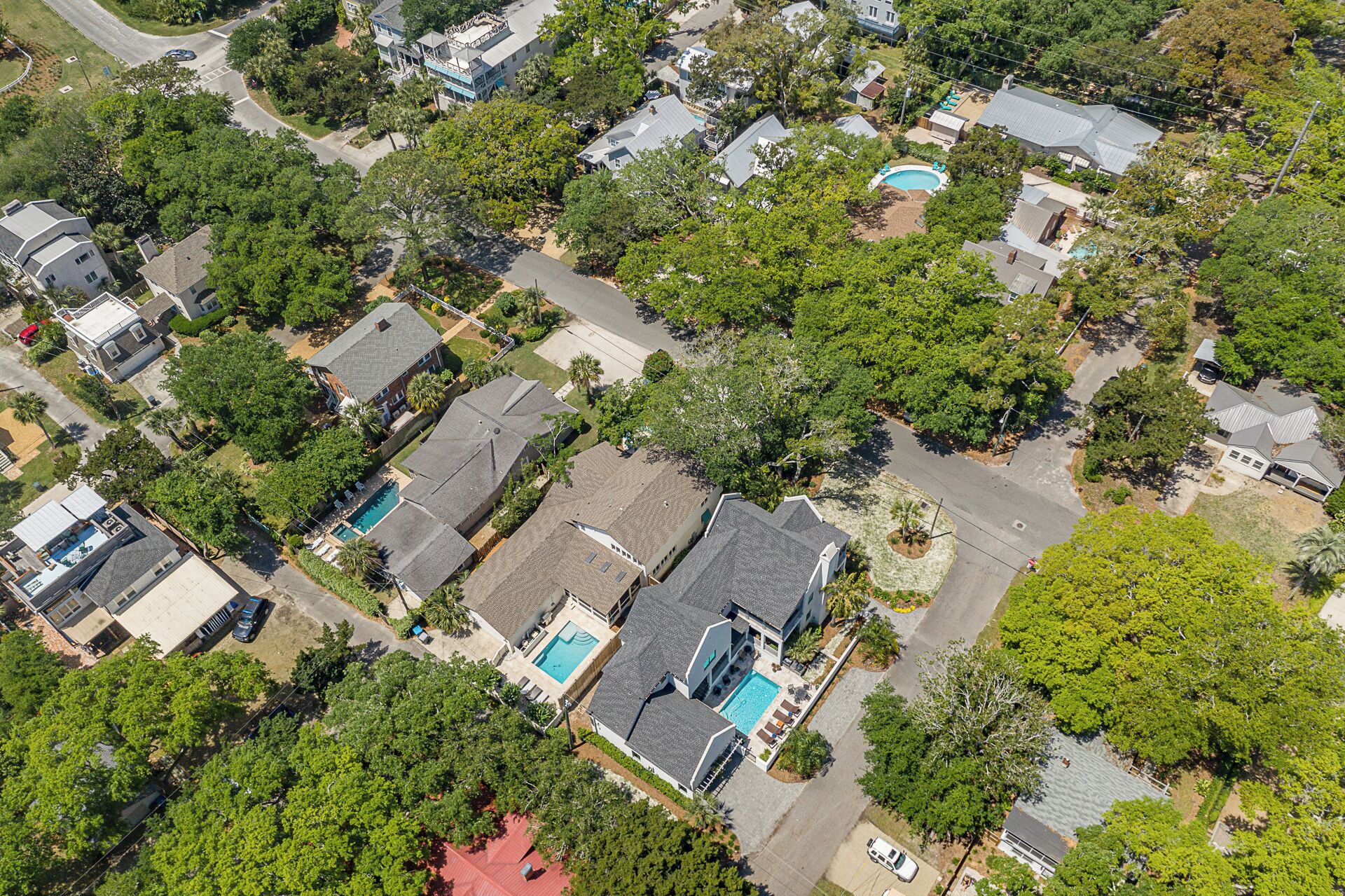 An aerial view of a residential area with houses, trees, and a swimming pool.