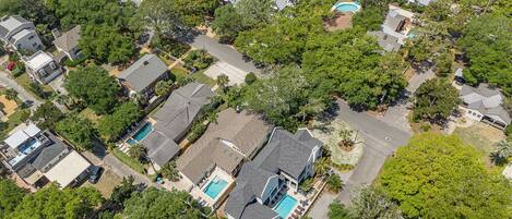 An aerial view of a residential area with houses, trees, and a swimming pool.