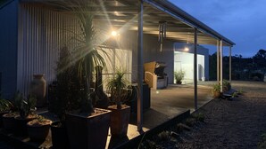 A covered outdoor area with potted plants, a seating area, and a building entrance.