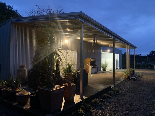 A covered outdoor area with potted plants, a seating area, and a building entrance. - Rural property with views of Rangataua Bay (Tauranga)