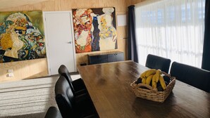 A conference room with a wooden table, black chairs, a basket of bananas, and two large abstract paintings on the wall.