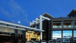 A modern hotel with a glass facade, multiple balconies, and a parking area. - Bela Hotel (Ternate)