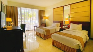A hotel room with two beds, a desk, a chair, a TV, and a large mirror. - Bela Hotel (Ternate)