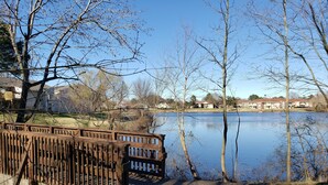 A lakeside park with a wooden fence, a concrete pathway, and houses in the background. - Super Nice townhouse in Virginia Beach (Virginia Beach)