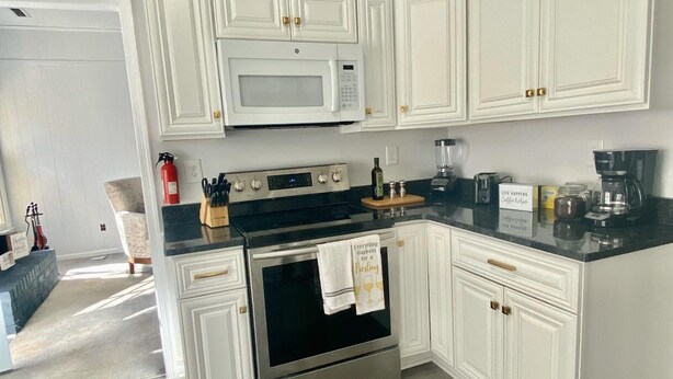 A modern kitchen with white cabinetry, stainless steel appliances, and a black countertop. - Super Nice townhouse in Virginia Beach (Virginia Beach)