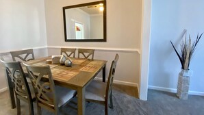 A dining room with a rectangular table, six chairs, a mirror, and a vase with decorative branches. - Super Nice townhouse in Virginia Beach (Virginia Beach)