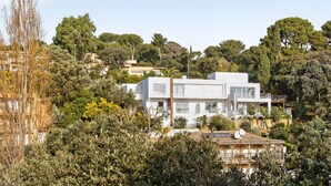 A modern two-story house with a flat roof, surrounded by dense greenery and trees. - Studio Aloe - Welkeys (Cavalaire-sur-Mer)