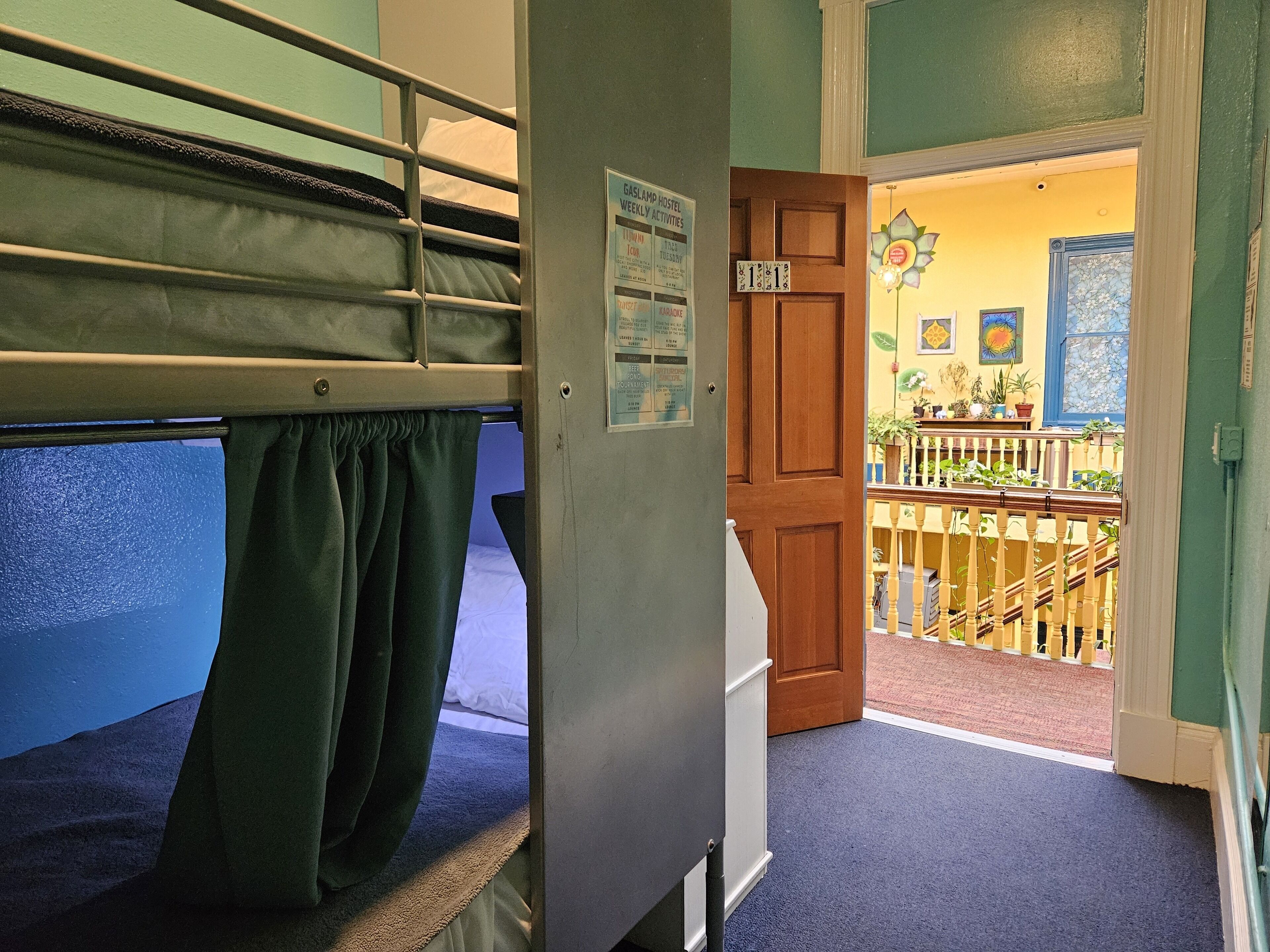 A bunk bed room with a wooden door leading to a balcony with a railing and potted plants.