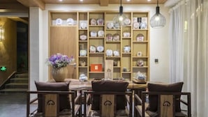 A dining area with a wooden table and chairs, a vase of flowers, and shelves with various dishes. - Floral Hotel · Zai Yi Qi Lijiang (Lijiang)