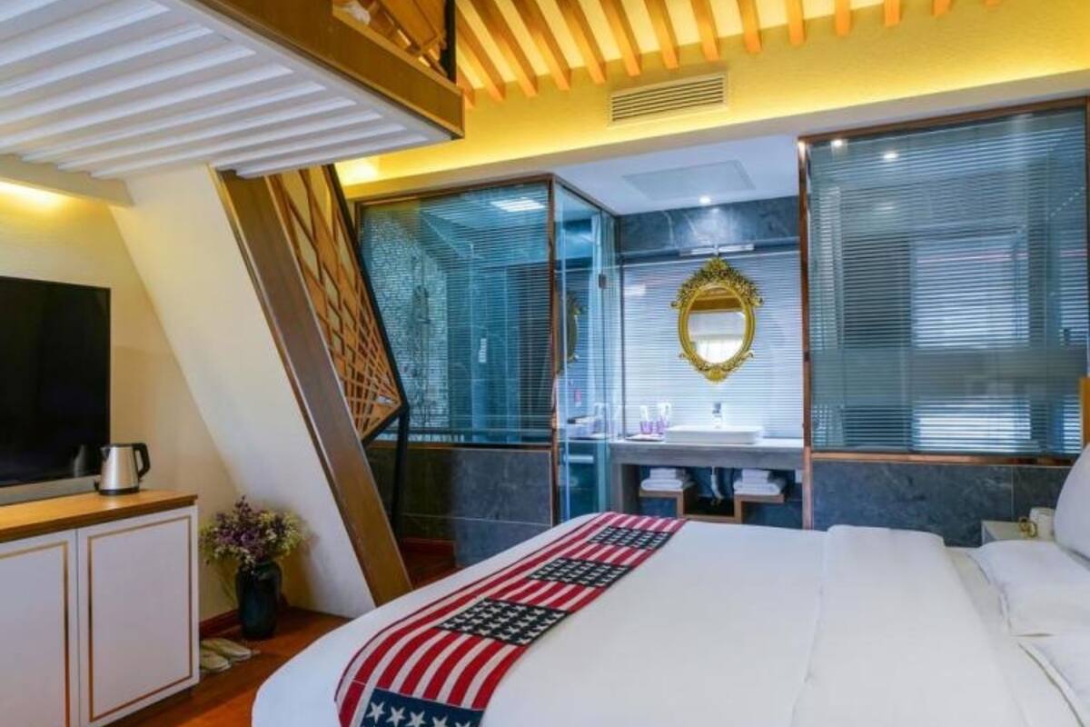 A modern hotel room with a large bed, a television, and a kitchenette.
