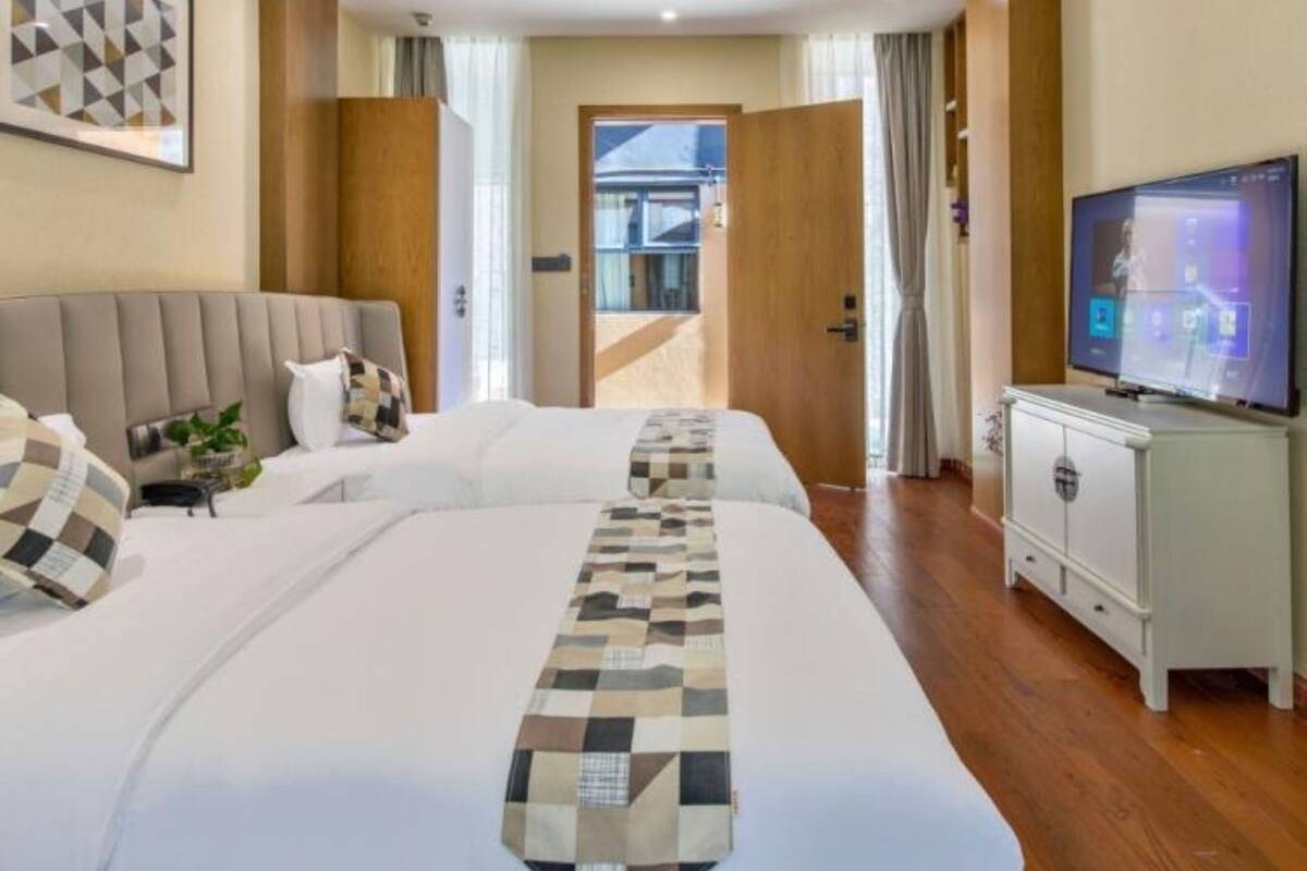 A hotel room with two beds, a television, a cabinet, and a view of the outside.
