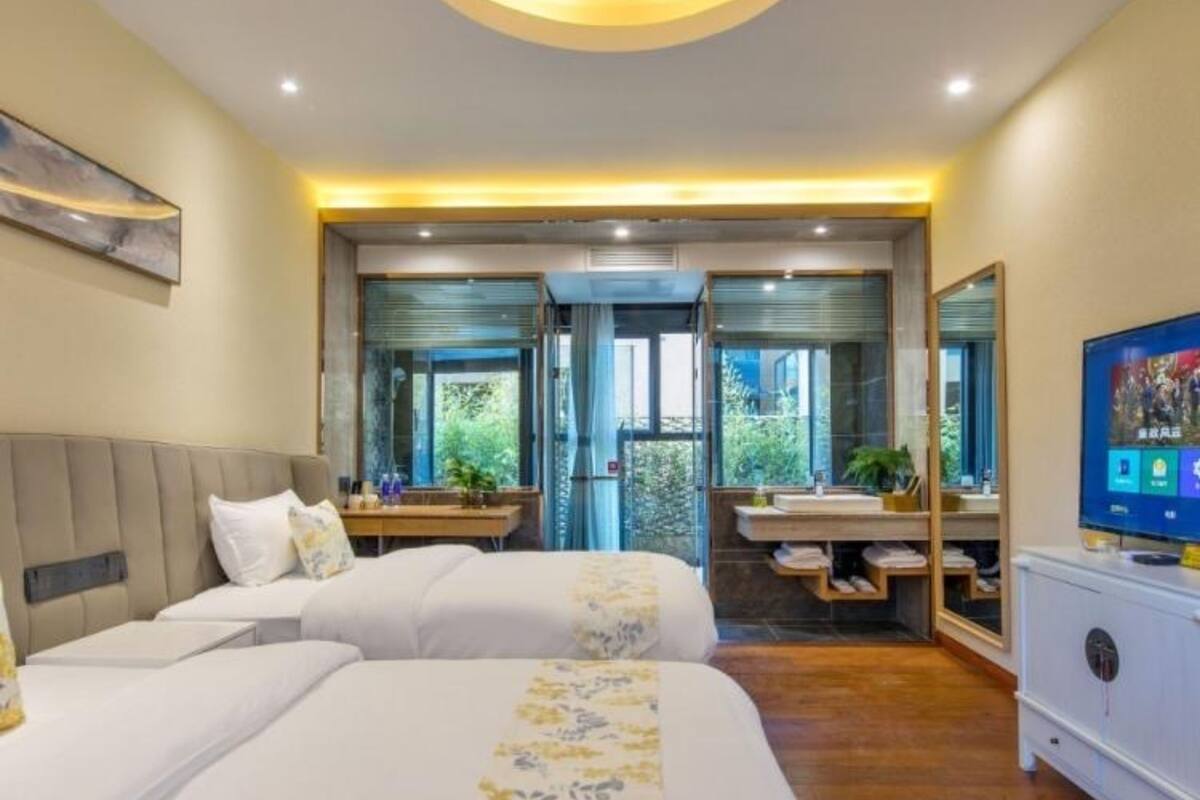 A modern hotel room with two beds, a desk, and a TV.