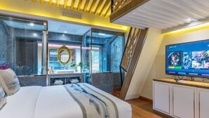 A modern bedroom with a large bed, a TV, and a view of the city. - Floral Hotel · Zai Yi Qi Lijiang (Lijiang)