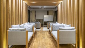 A hotel room with a wooden floor, a bed, two white sofas, and a TV screen. - Floral Hotel · Zai Yi Qi Lijiang (Lijiang)