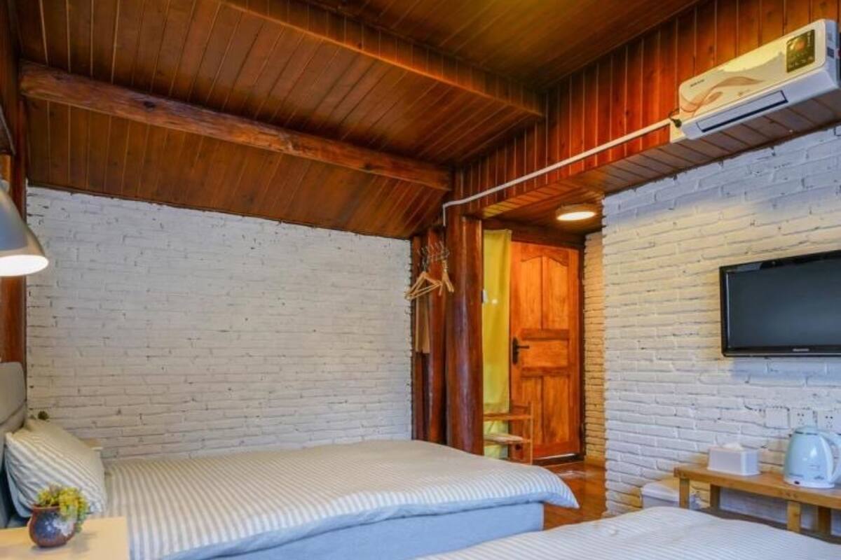 Una habitación acogedora con dos camas, un televisor y techo de madera.