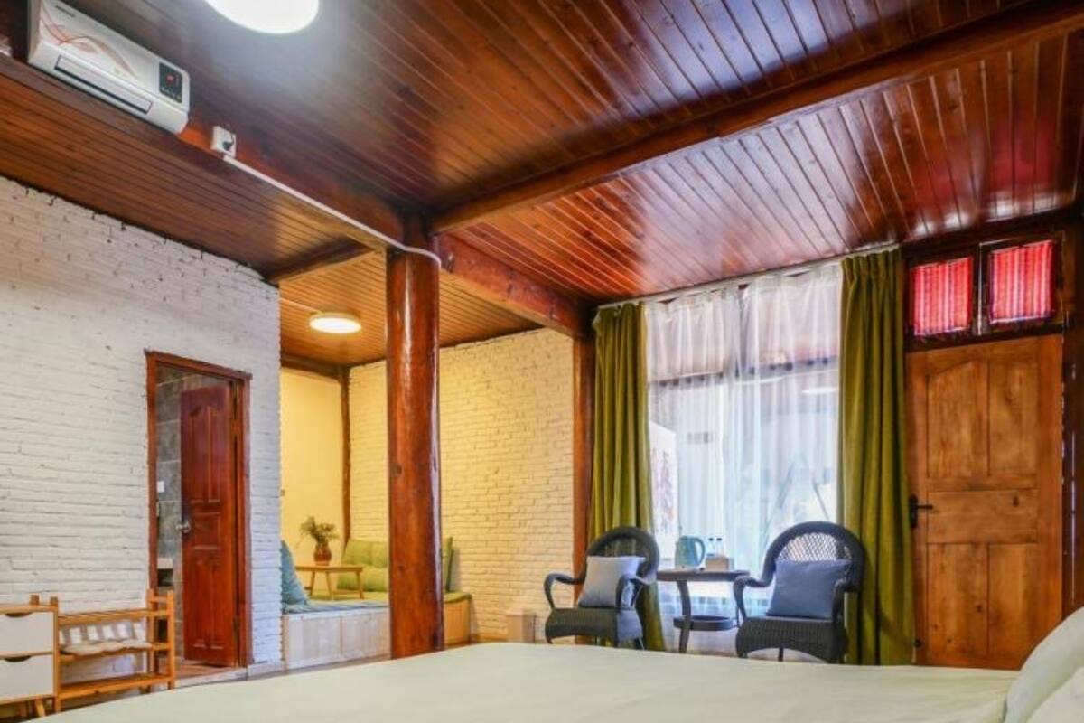 Un dormitorio con una cama, techo de madera, pared de ladrillo y una ventana con cortinas.