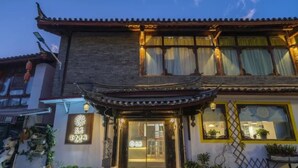 A traditional building with a tiled roof, a wooden entrance with glass doors, and a sign with Chinese characters. - Floral Hotel · Kuan Tang Lijiang (Lijiang)