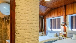 A bedroom with two beds, wooden walls, a brick column, and a bathroom with a shower. - Floral Hotel · Kuan Tang Lijiang (Lijiang)