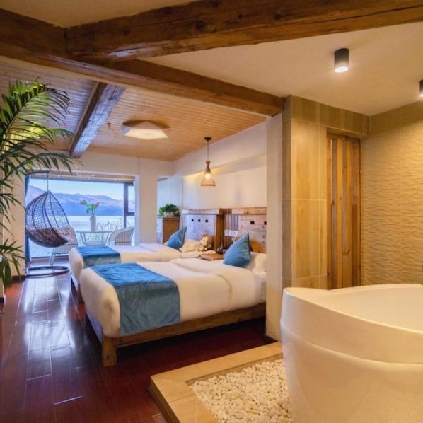 A bedroom with two beds, a large bathtub, and a view of the mountains.