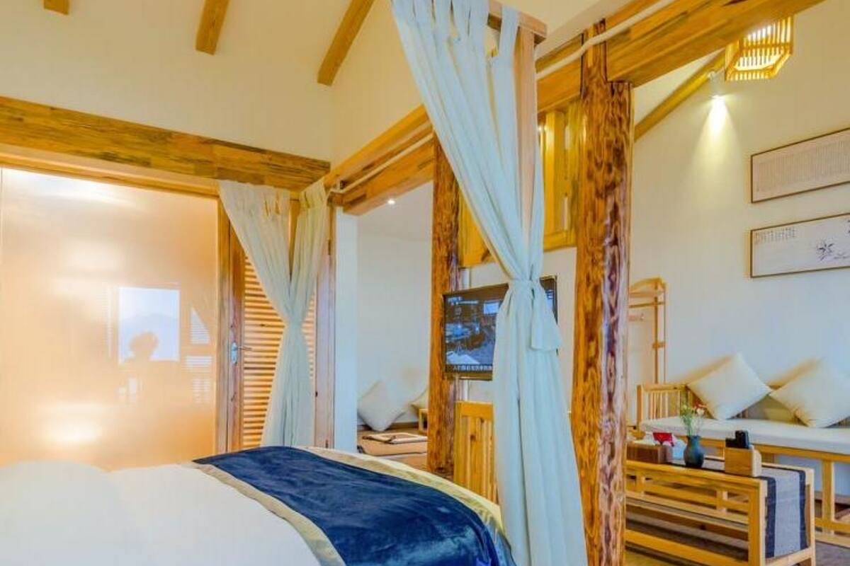 Un dormitorio con una cama, un banco de madera y un televisor montado en la pared.