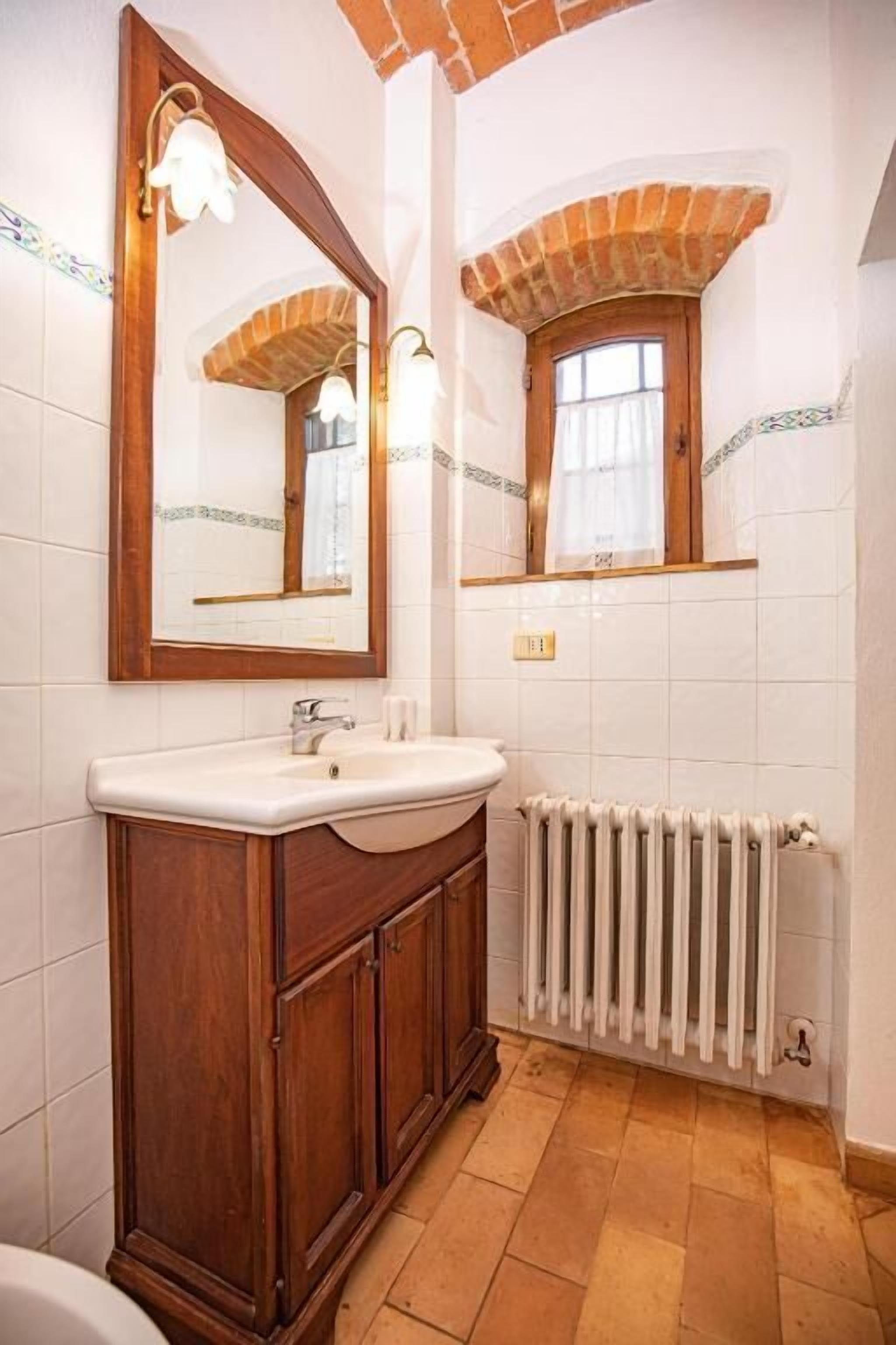 Une salle de bain avec un meuble-lavabo en bois, un grand miroir et un radiateur.