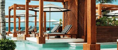 Relax by the pool surrounded by palm trees and ocean views.