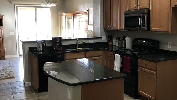 A kitchen with wooden cabinets, a black countertop, a built-in microwave, and a stove. - Experience Casa Grande charm in our spacious 4-bedroom retreat (Casa Grande)