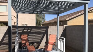 A covered patio area with two lounge chairs and a pergola structure. - Experience Casa Grande charm in our spacious 4-bedroom retreat (Casa Grande)
