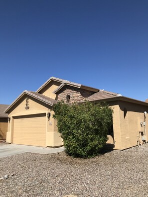 A residential house with a garage, a small garden, and a clear blue sky.
