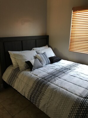 A bed with a geometric patterned bedspread, a dark headboard, and multiple pillows.