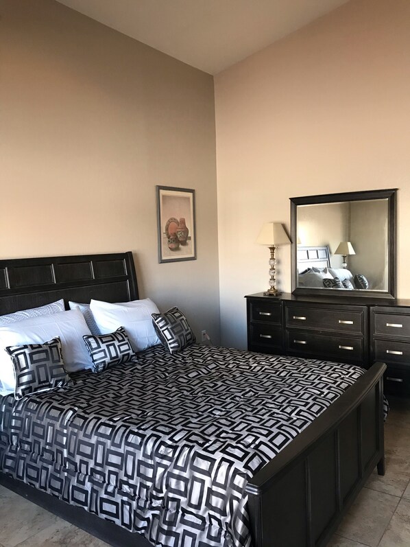 Un dormitorio con una cama grande, un aparador, un espejo y un cuadro en la pared.