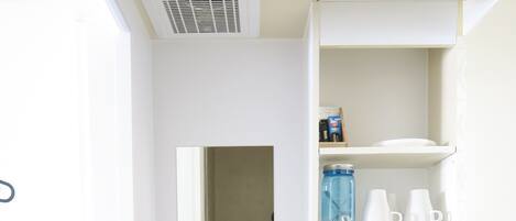 Een magnetron, een waterkoker, kookgerei, borden en bestek, keukenrol