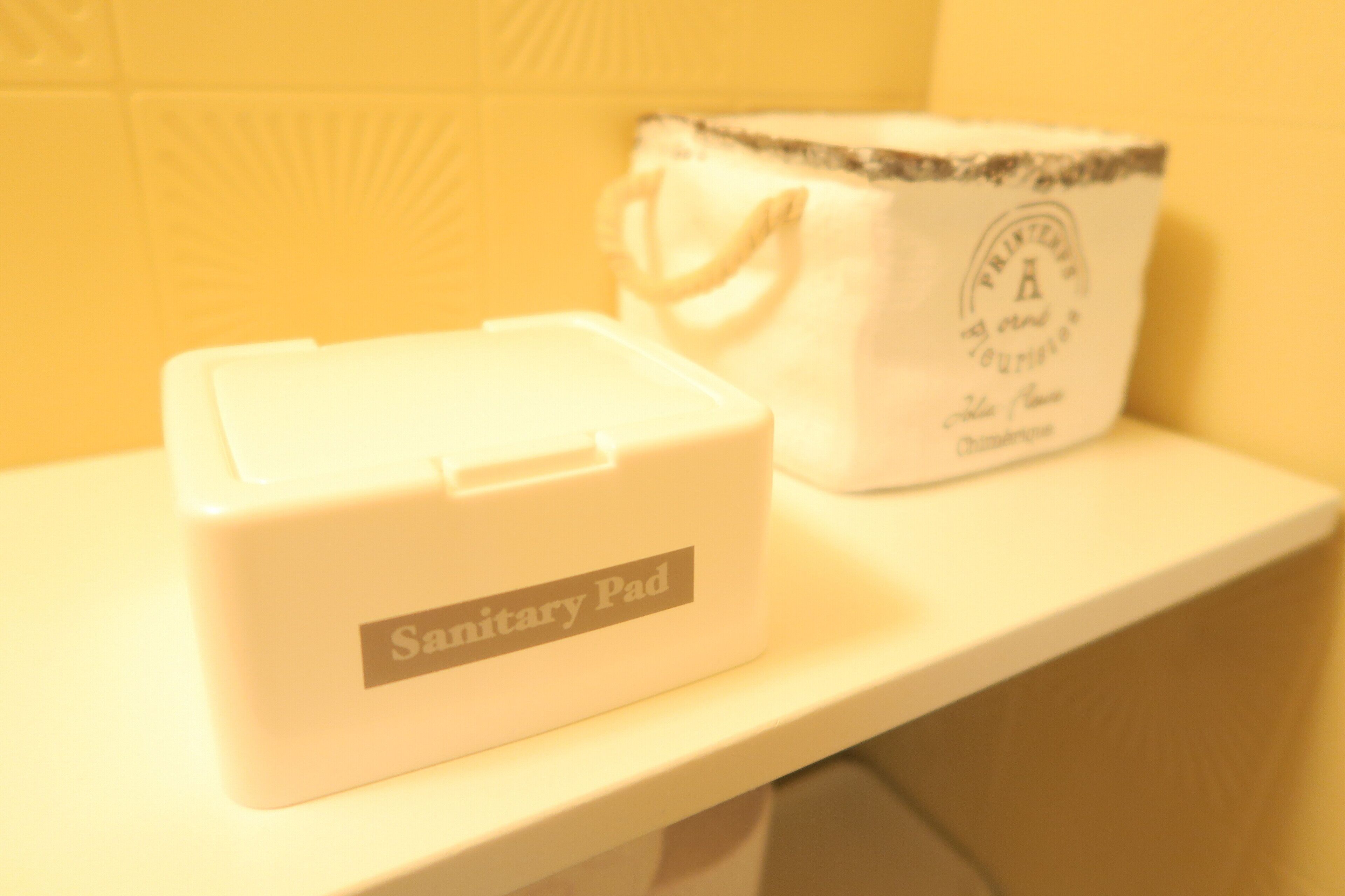 Une protection hygiénique et un sac orné d’un logo, le tout posé sur une surface blanche.
