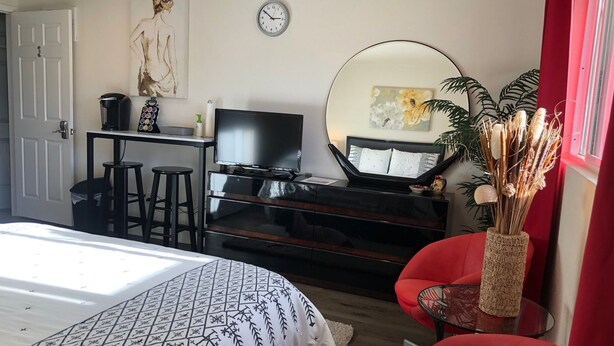 Ett sovrum med en säng, en tv, ett skrivbord och en röd stol.
