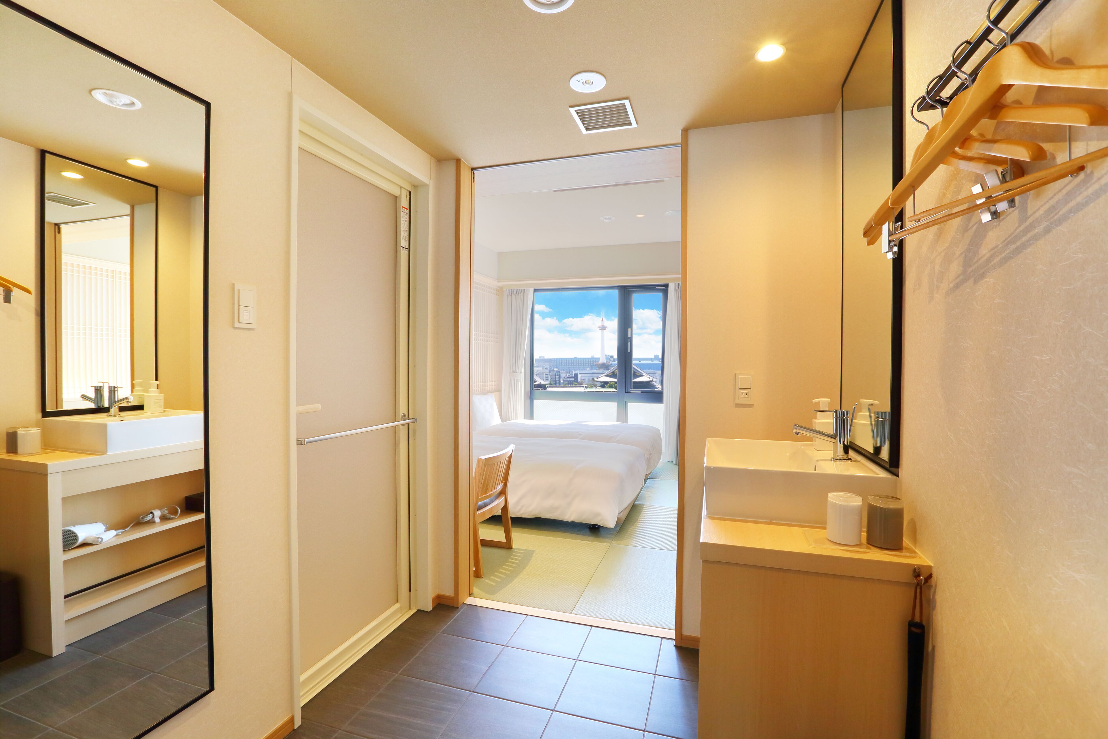 Une chambre d’hôtel avec un grand lit, une salle de bain avec un lavabo et un miroir, et une vue sur la ville.