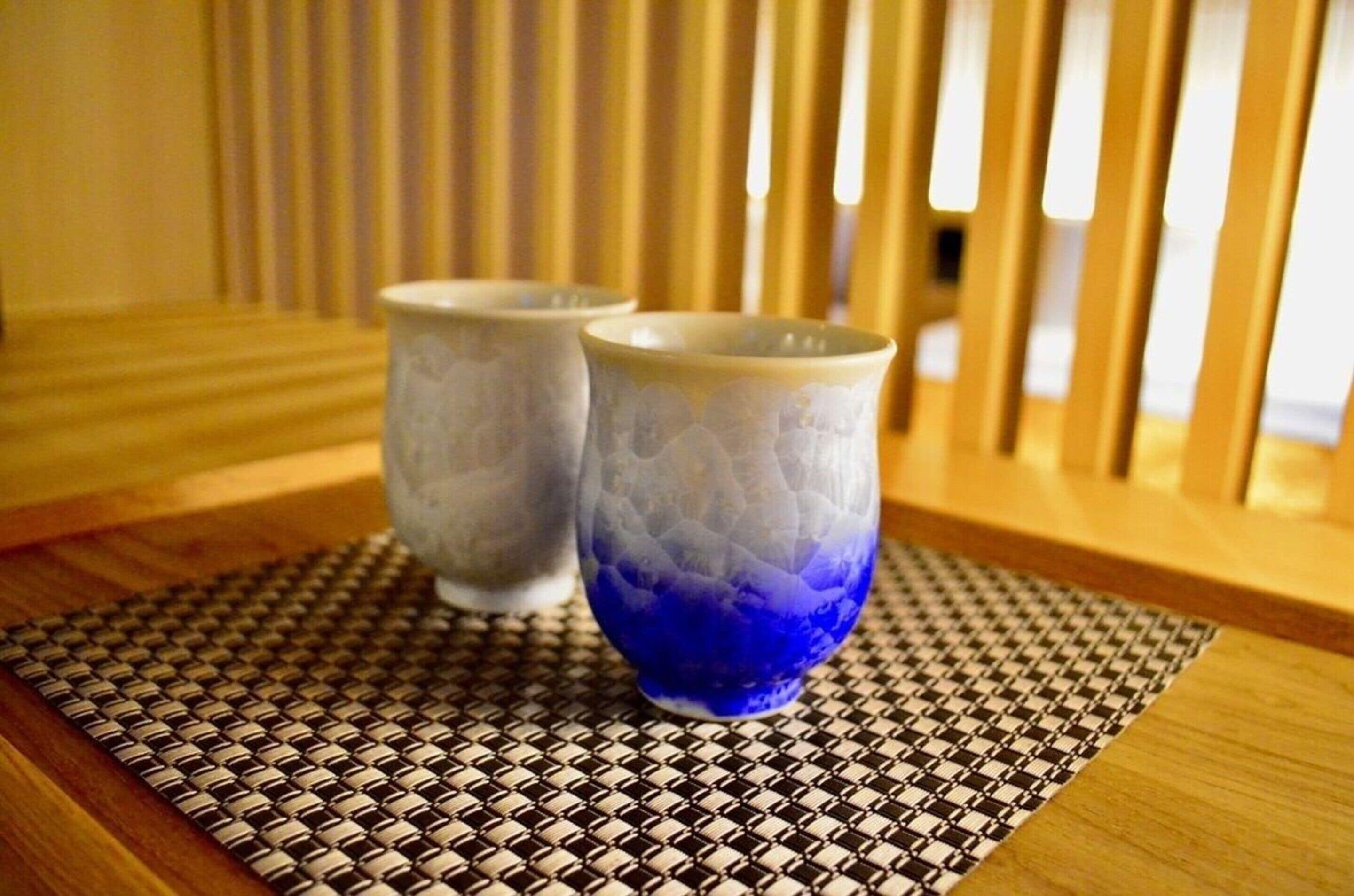 Two ceramic cups on a woven placemat.