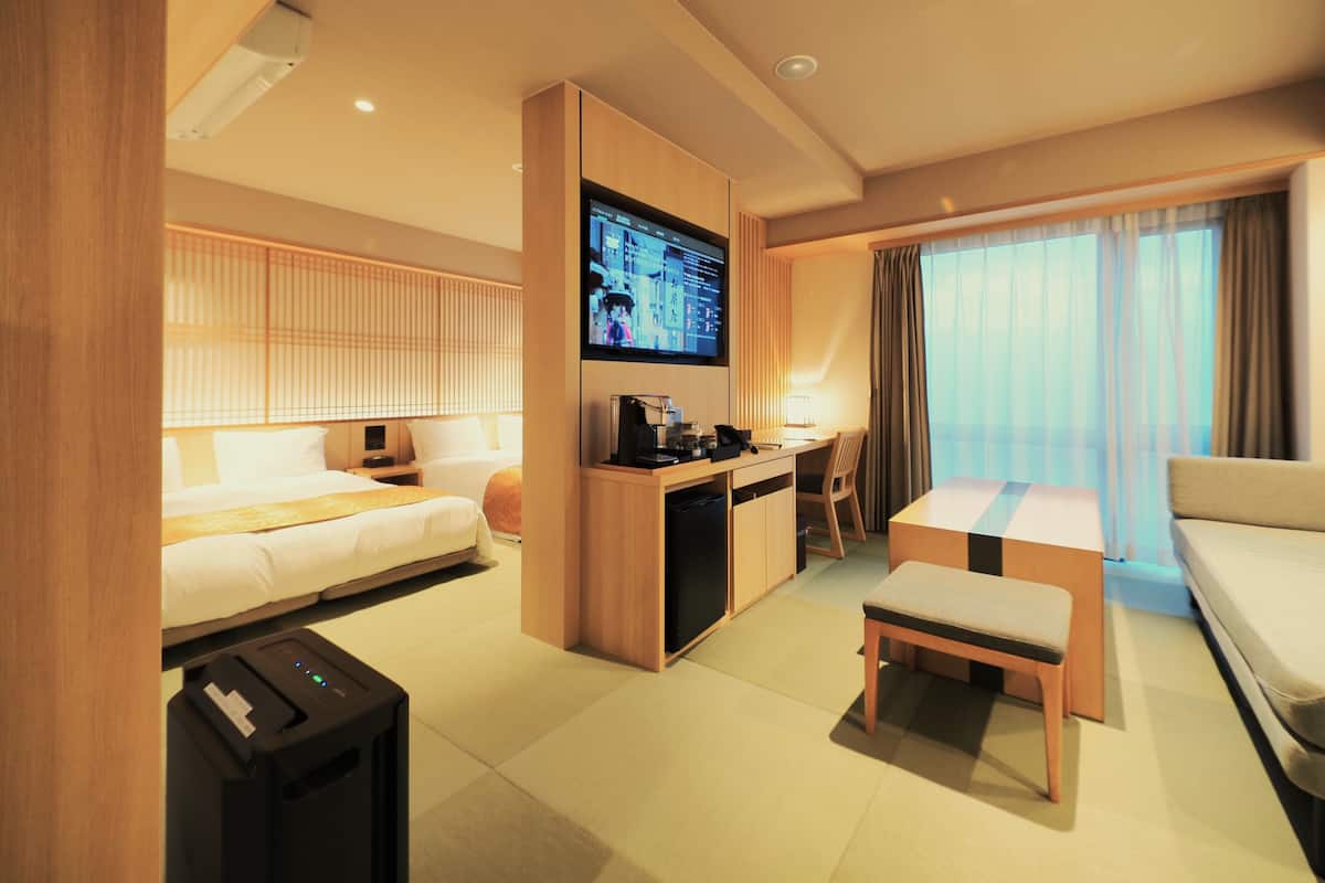 A hotel room with a bed, desk, chair, and a television.