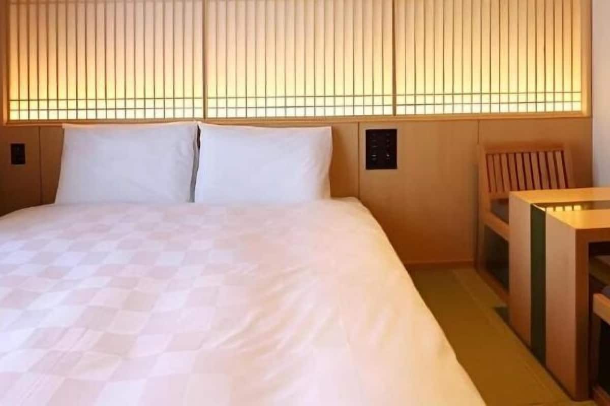A hotel room with a bed, a small table, and a chair.