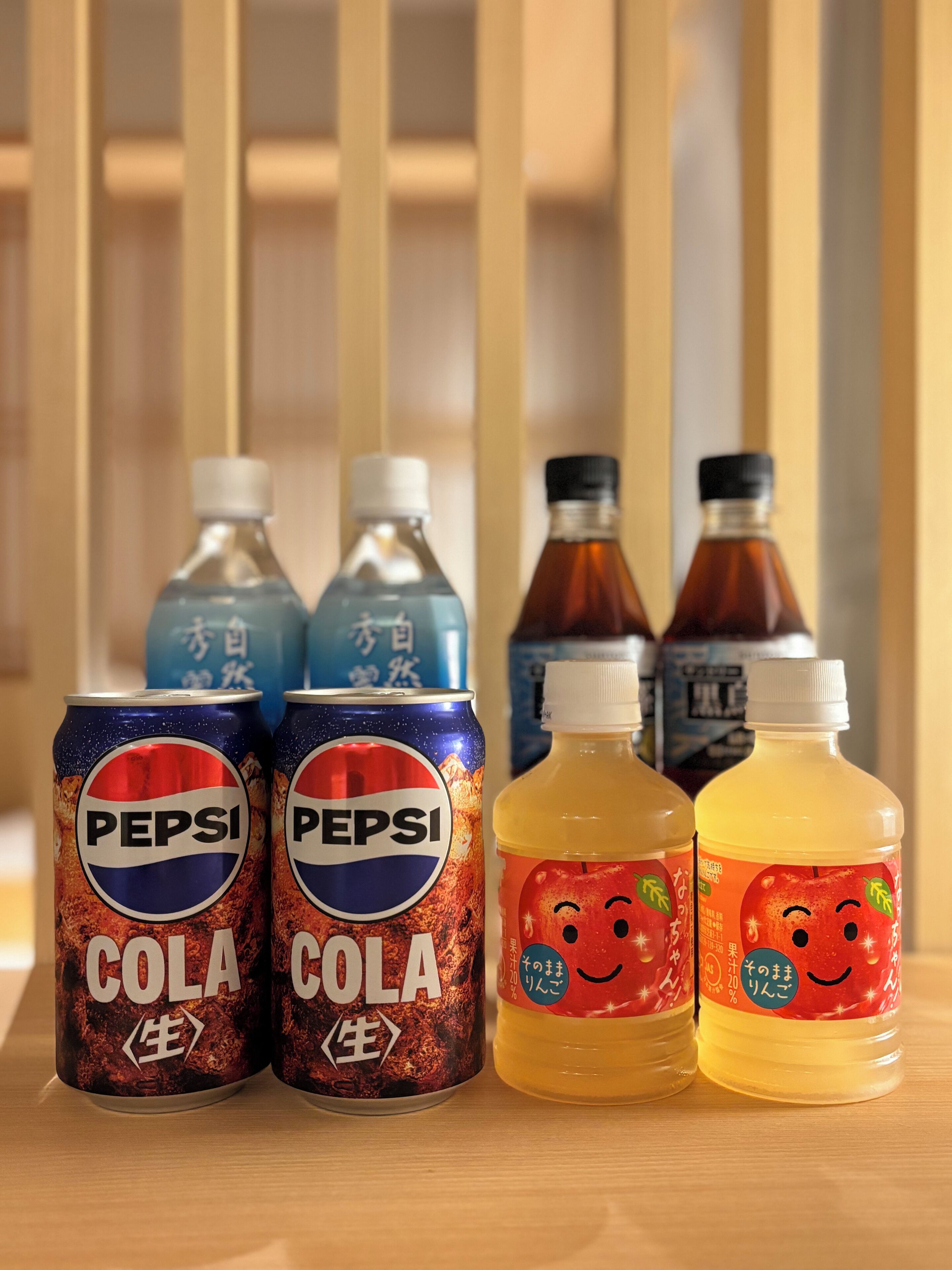 Four beverage cans and two bottles on a wooden surface.