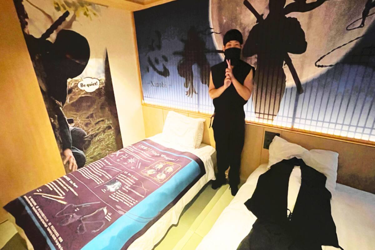 A hotel room with a bed, a window with blinds, and a wall with a poster.