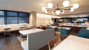 Un restaurant moderne avec des tables hautes, des banquettes et un espace bar.