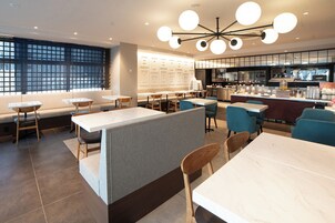Un restaurante moderno con mesas altas, cabinas y una zona de bar.
