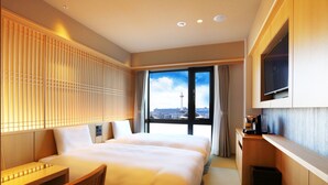 Une chambre d’hôtel avec un grand lit, un bureau, une télévision et une vue sur une tour.
