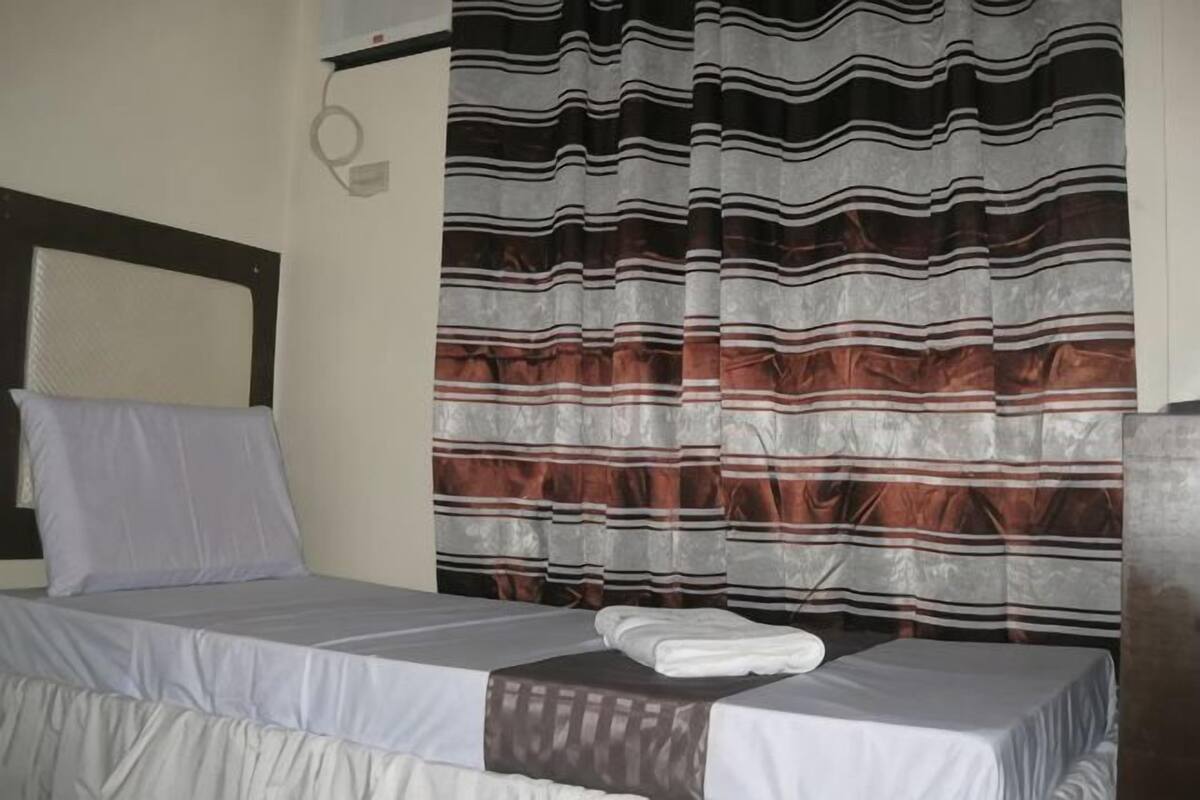 A bed with a white bedspread, a pillow, and a folded towel.