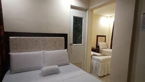 Habitación de hotel con una cama, una puerta que da a un baño y una mesita con una silla.