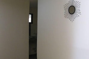 Un pasillo con un espejo en la pared y una puerta que da a otra habitación.
