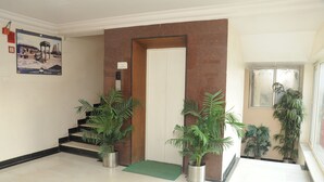Een schone, moderne lobby met een trap, potplanten en een deur met een bord erboven.