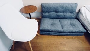 A modern room with a grey sofa, a white chair, and a small wooden table. - Hostel 758 Nagoya3A (Nagoya)