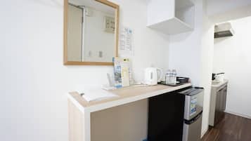 A compact kitchenette with a countertop, a kettle, a coffee maker, and a small refrigerator.